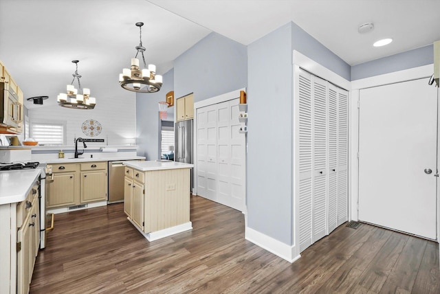 kitchen featuring cream cabinets, a center island, appliances with stainless steel finishes, pendant lighting, and dark hardwood / wood-style flooring