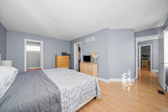 bedroom featuring light wood-type flooring, a closet, and a walk in closet