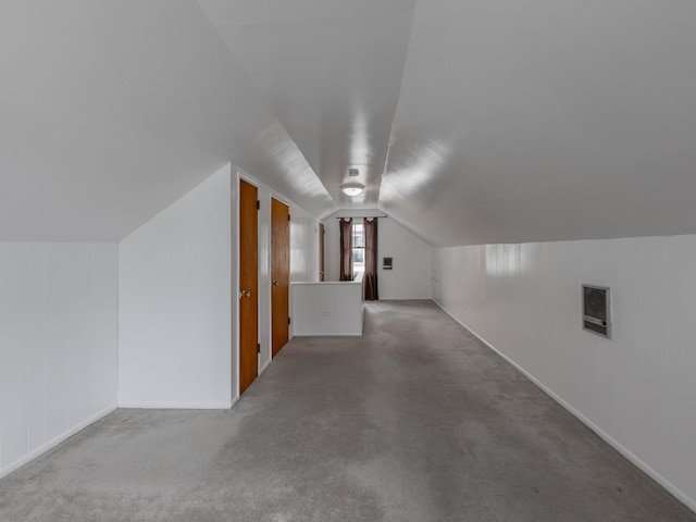 additional living space featuring vaulted ceiling and carpet flooring