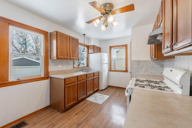 kitchen featuring light hardwood / wood-style floors, ceiling fan, white appliances, hanging light fixtures, and sink