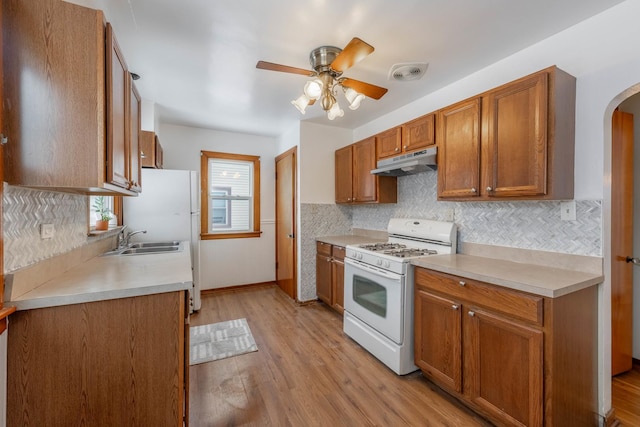 kitchen with ceiling fan, sink, gas range gas stove, and light hardwood / wood-style flooring