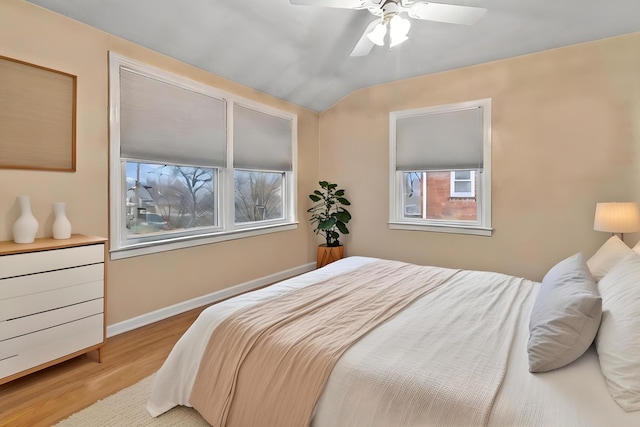 bedroom with ceiling fan, multiple windows, light wood-type flooring, and vaulted ceiling