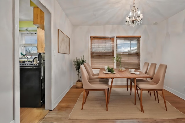 dining room with light hardwood / wood-style floors and a notable chandelier