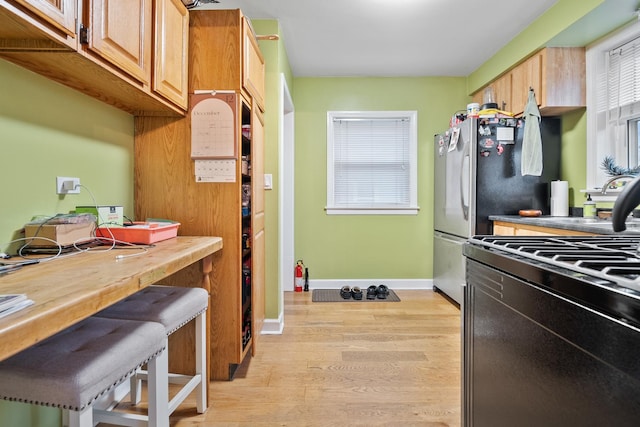 kitchen featuring sink, butcher block counters, black range, and light wood-type flooring