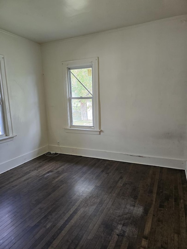 empty room with dark wood-type flooring and ornamental molding