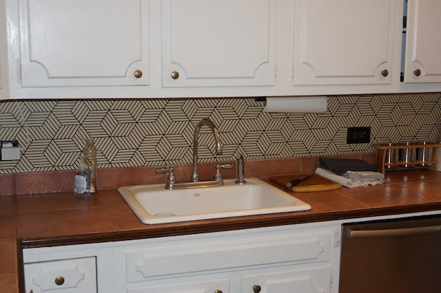 kitchen featuring stainless steel dishwasher, sink, decorative backsplash, and white cabinets