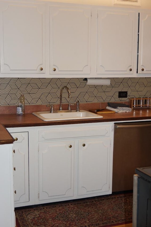 kitchen with tasteful backsplash, white cabinetry, and sink