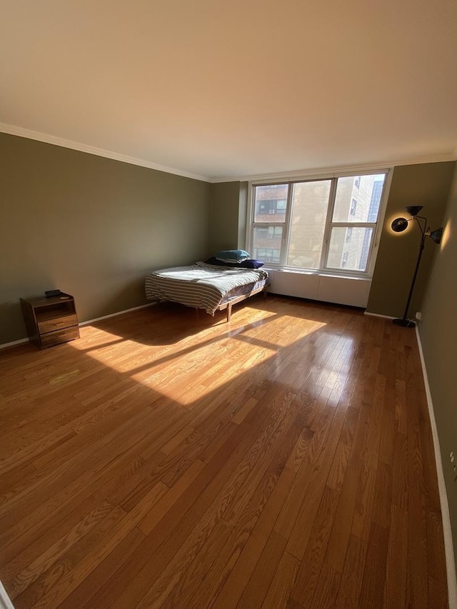 unfurnished bedroom featuring crown molding and hardwood / wood-style floors