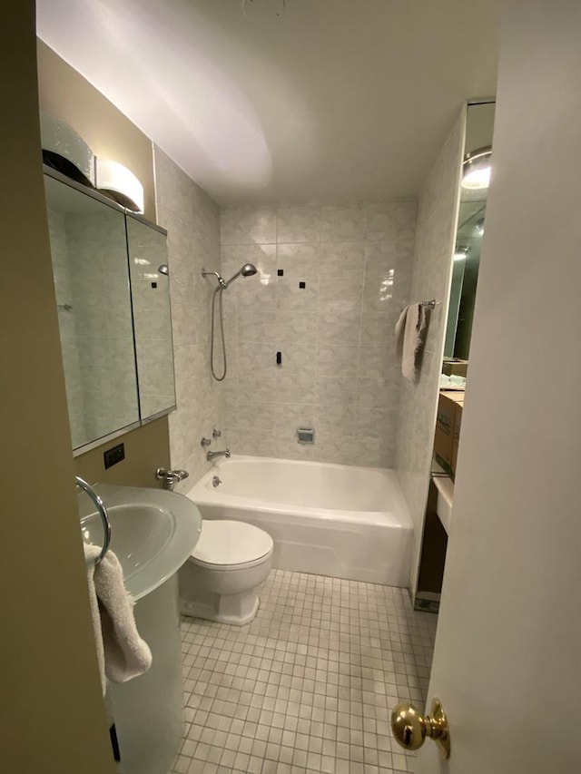 bathroom with tiled shower / bath combo, tile patterned flooring, and toilet