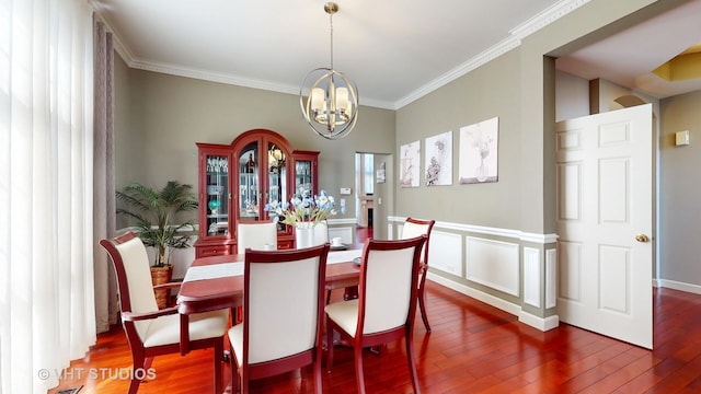 dining area with dark wood-type flooring, an inviting chandelier, and ornamental molding