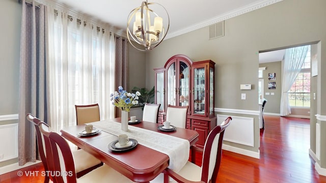 dining room featuring dark hardwood / wood-style floors, crown molding, and a notable chandelier