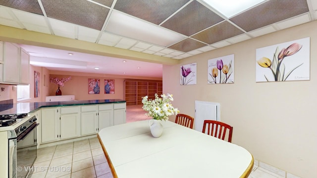 tiled dining area featuring a drop ceiling