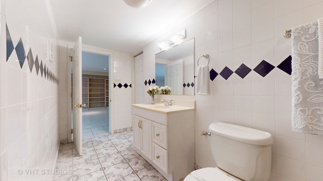 bathroom with toilet, vanity, and tile walls