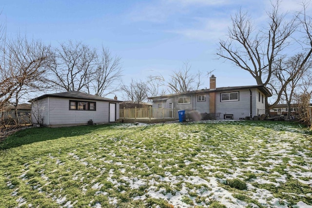 snow covered back of property with a deck and a yard