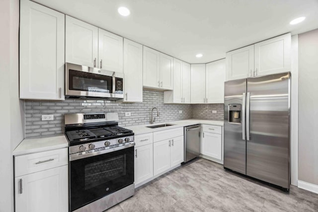 kitchen featuring white cabinetry, stainless steel appliances, tasteful backsplash, light hardwood / wood-style floors, and sink