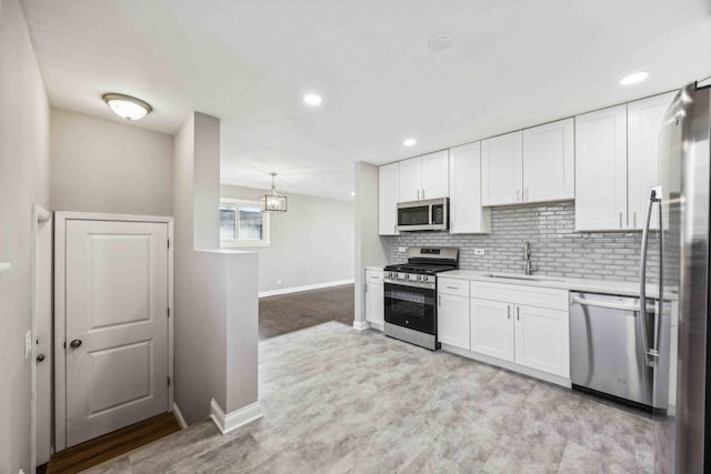 kitchen with sink, white cabinetry, hanging light fixtures, and appliances with stainless steel finishes