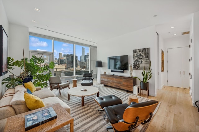 living room with a wall of windows and light hardwood / wood-style flooring