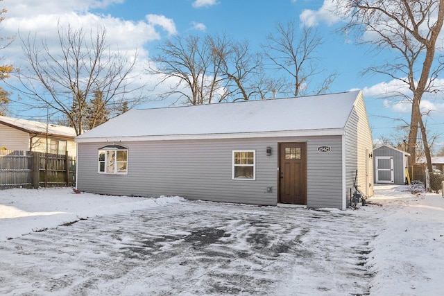 snow covered house featuring a shed