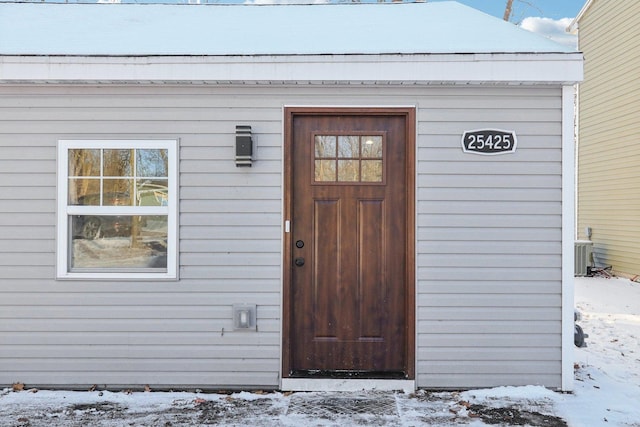 snow covered property entrance with cooling unit