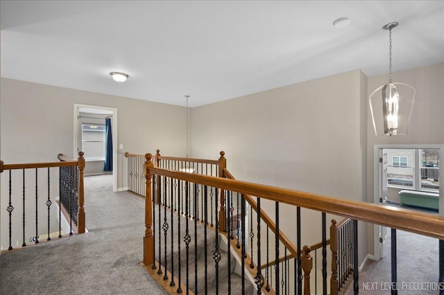 hallway featuring an inviting chandelier, a wealth of natural light, and carpet flooring