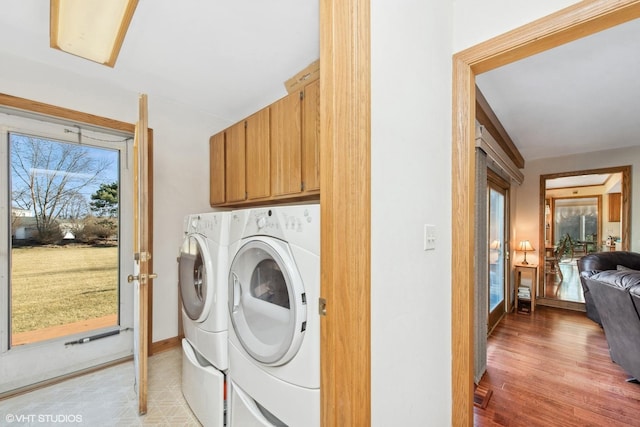 laundry room with cabinets, washing machine and dryer, and light hardwood / wood-style flooring