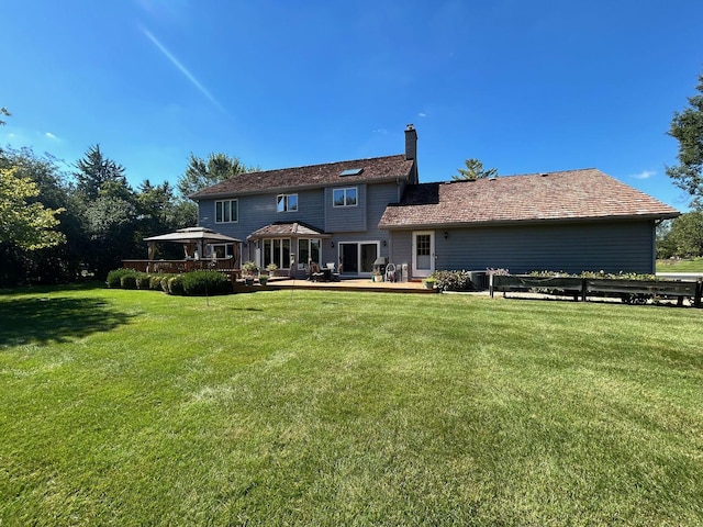 back of house featuring a wooden deck, a gazebo, and a lawn