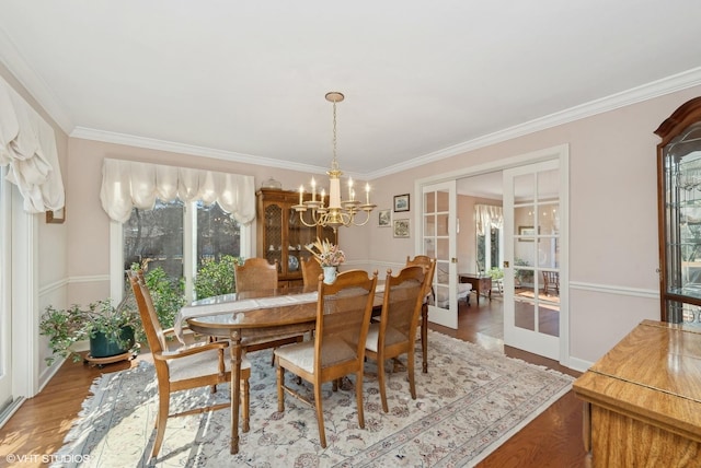 dining room with hardwood / wood-style flooring, ornamental molding, a notable chandelier, and french doors