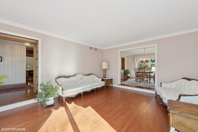 living area featuring hardwood / wood-style flooring, crown molding, and a chandelier