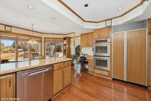 kitchen with crown molding, light stone counters, wood-type flooring, hanging light fixtures, and appliances with stainless steel finishes