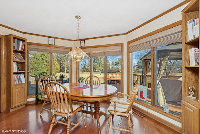 dining room featuring dark wood-type flooring, crown molding, and a notable chandelier