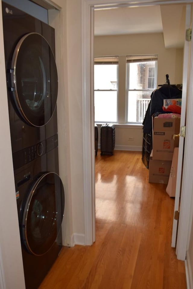 laundry area with light wood-type flooring and stacked washer / drying machine