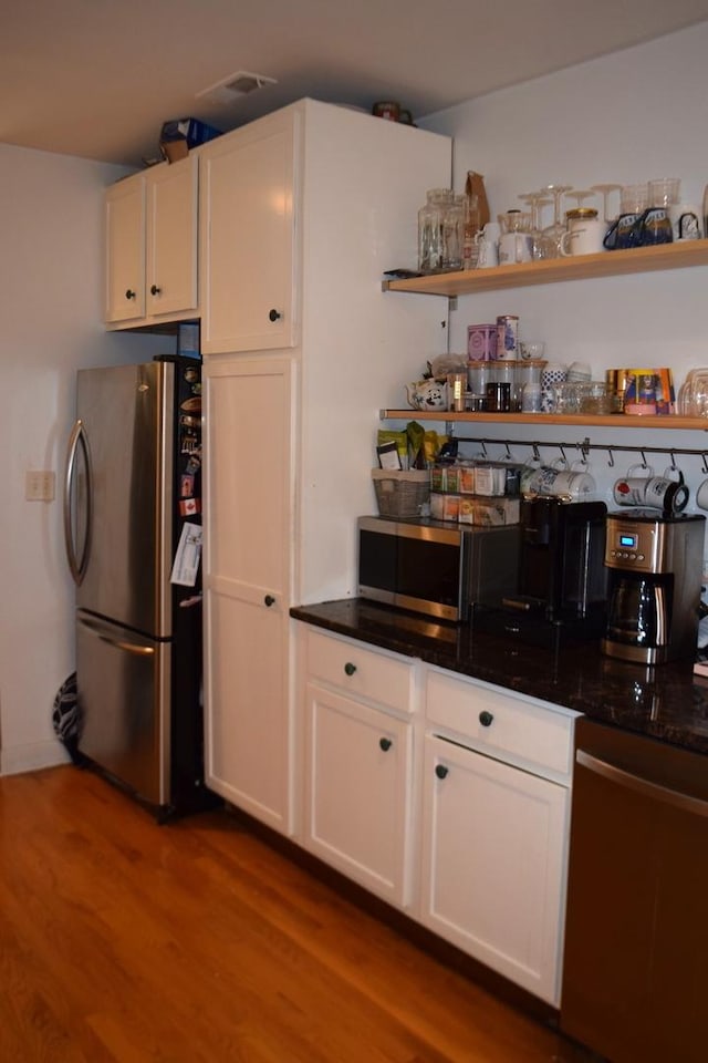 kitchen featuring wood-type flooring, white cabinets, and stainless steel appliances