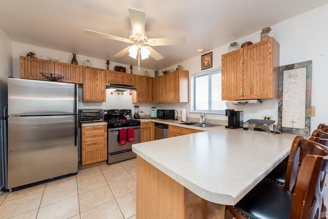 kitchen with appliances with stainless steel finishes, sink, a kitchen breakfast bar, kitchen peninsula, and light tile patterned floors