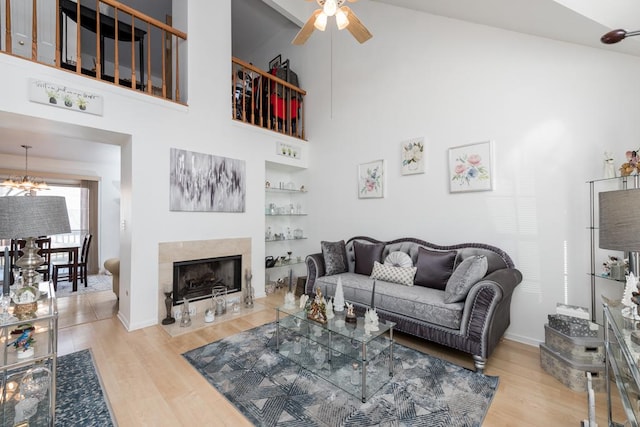 living room featuring light wood-type flooring, ceiling fan with notable chandelier, and high vaulted ceiling