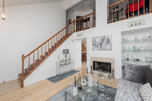 living room featuring wood-type flooring, a fireplace, and a towering ceiling