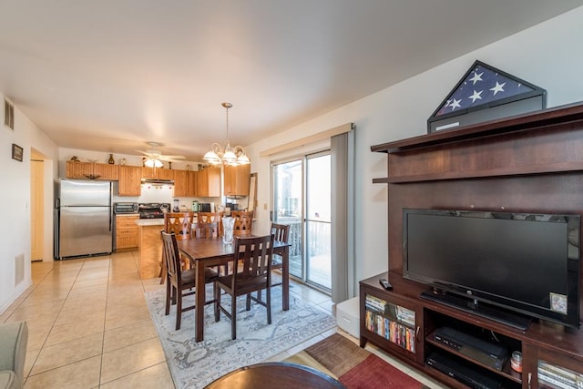 dining space with ceiling fan with notable chandelier and light tile patterned floors