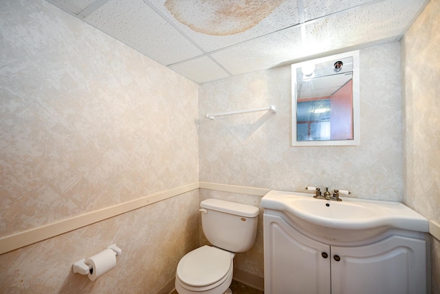 bathroom with vanity, toilet, and a drop ceiling