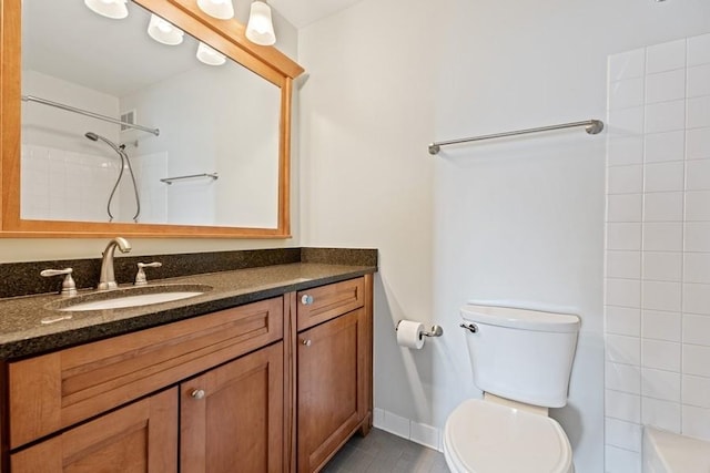 bathroom featuring toilet, a tile shower, and vanity