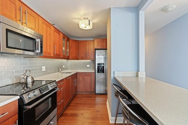 kitchen with backsplash, hardwood / wood-style floors, sink, stainless steel appliances, and light stone counters