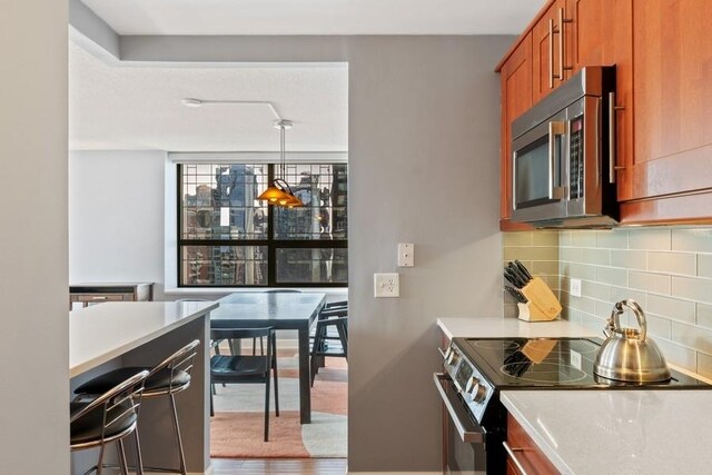 kitchen with backsplash, electric range, and hanging light fixtures