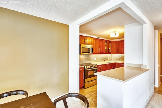 kitchen with sink, backsplash, stainless steel appliances, and a textured ceiling