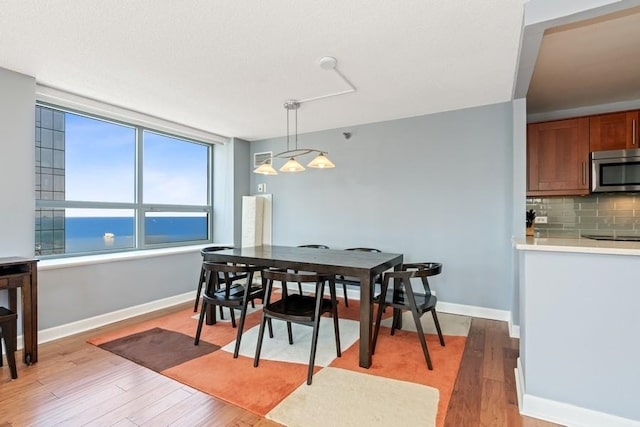 dining space featuring a water view and light wood-type flooring