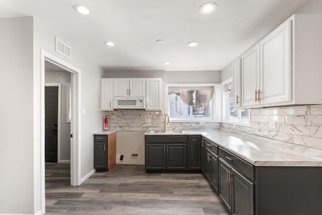 kitchen featuring sink, hardwood / wood-style flooring, white cabinetry, and tasteful backsplash