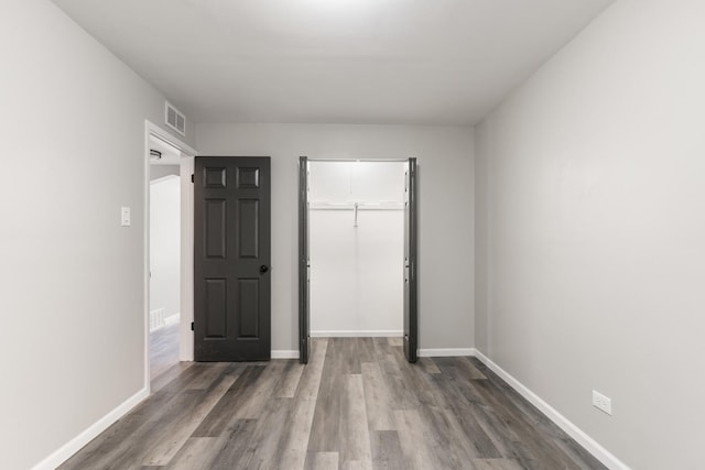 unfurnished bedroom with a closet and dark hardwood / wood-style floors