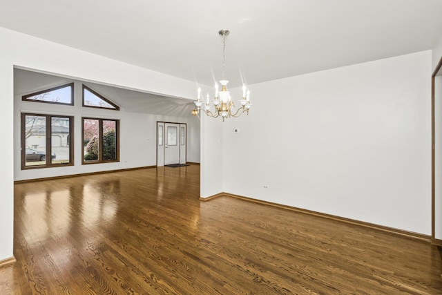 empty room featuring dark wood-type flooring, a chandelier, and lofted ceiling