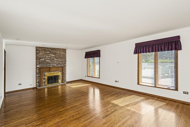 unfurnished living room featuring a brick fireplace and wood-type flooring