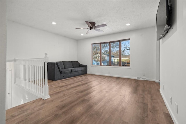 unfurnished living room with ceiling fan, hardwood / wood-style floors, and a textured ceiling