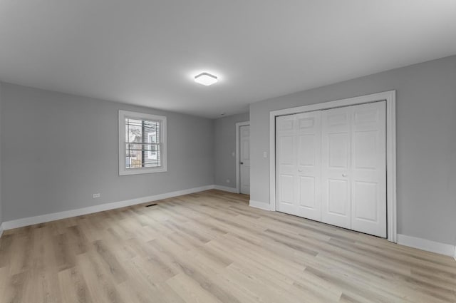 unfurnished bedroom with light wood-type flooring and a closet