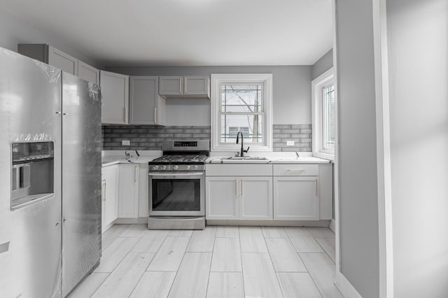 kitchen featuring decorative backsplash, sink, gray cabinets, and stainless steel appliances