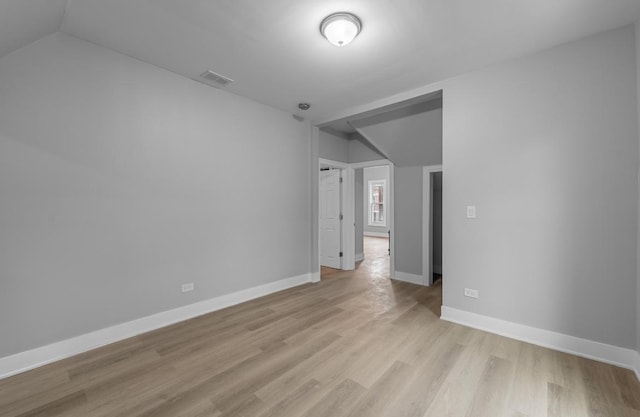 spare room with light hardwood / wood-style floors and vaulted ceiling